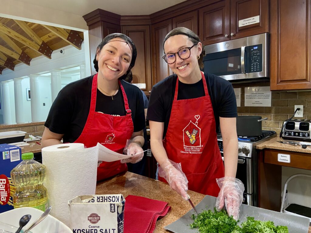 Two Strategic Wealth Designers volunteers smiling while preparing a meal in the Ronald McDonald House kitchen
